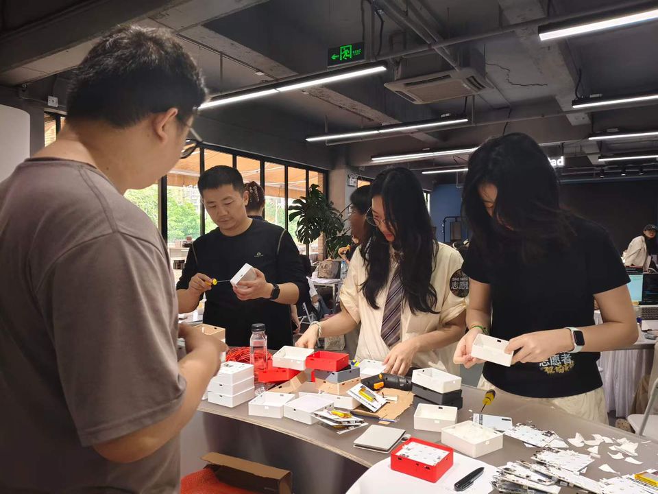 Participants assembling small electronics enclosures at a hardware hackathon