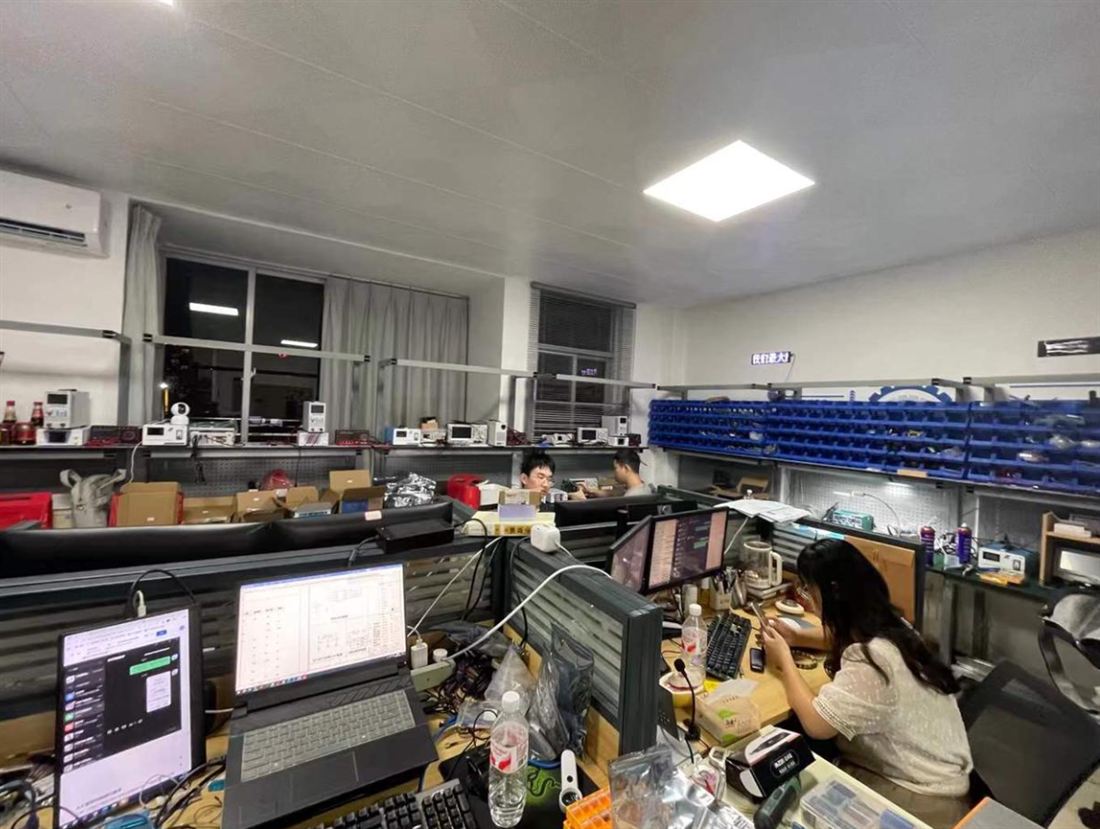 Our engineers at the debug bench in Shenzhen — instruments, parts bins and boards under test