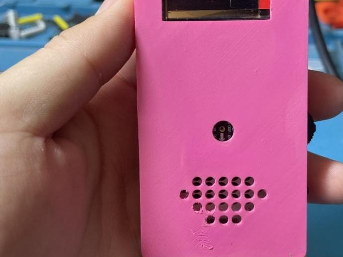 Pink handheld voice assistant with a speaker grille and display