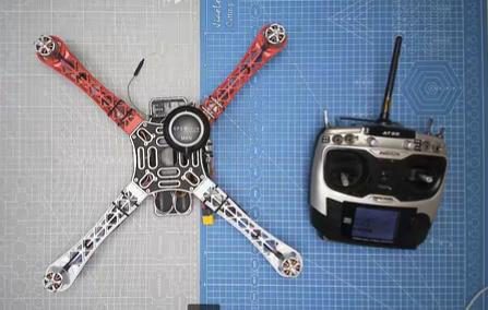 The quadcopter frame next to a handheld radio transmitter on cutting mats