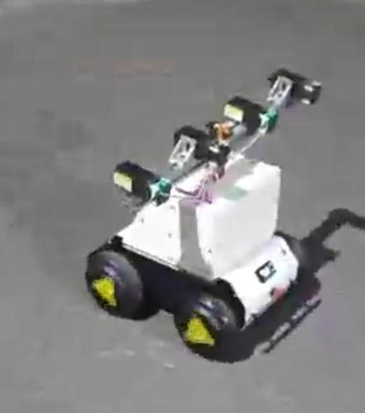 Blurry video frame of the white robot on grey ground with the laser beam turned sideways