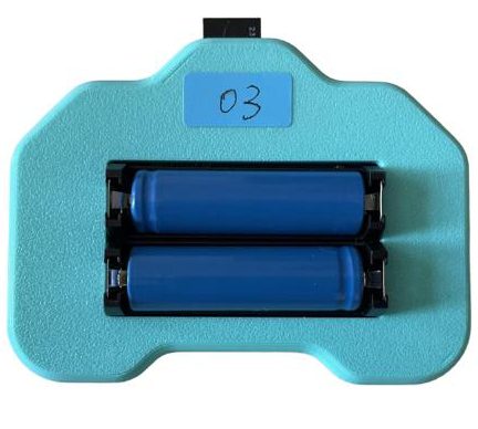 Back of the teal controller case with two blue cylindrical batteries in a holder and an '03' label