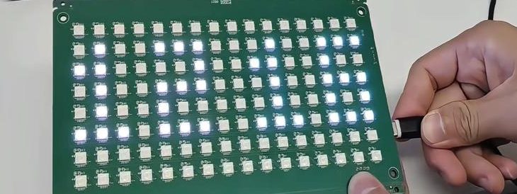 Hand plugging a USB cable into a green LED matrix board with rows of white LEDs lit