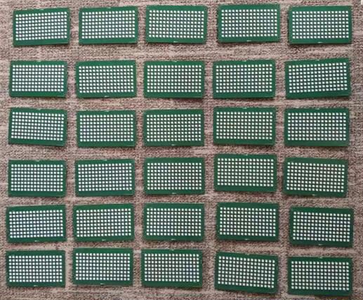 About thirty green LED matrix PCBs laid out in rows on a carpet