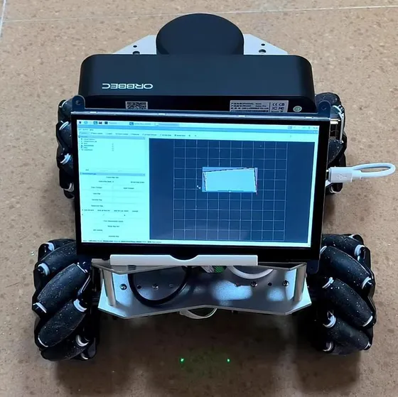 Front view of a mecanum-wheel robot on a tiled floor; a touchscreen on the front shows a mapping program with a grid, and a black depth camera sits on top