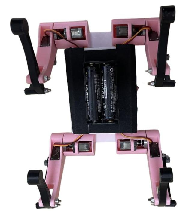 Underside of the pink quadruped showing a black two-cell battery holder between the legs