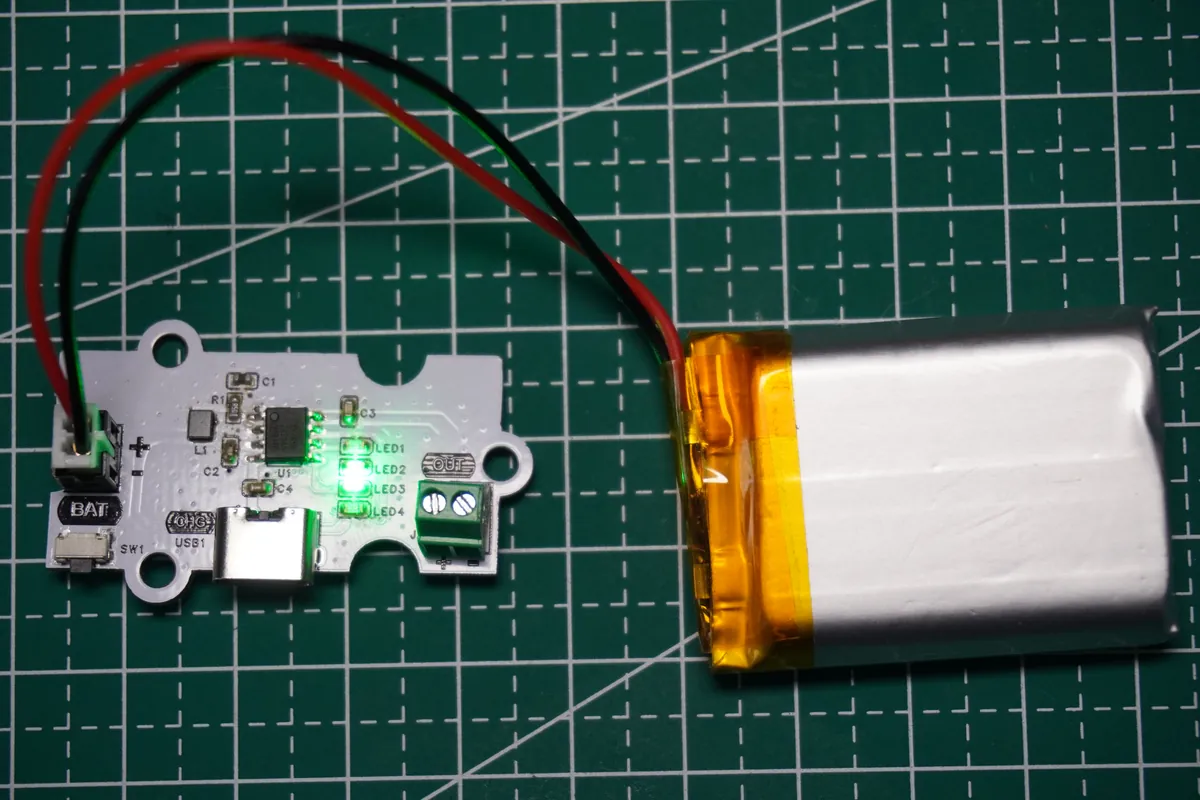 IP5407 battery module on a cutting mat with a lithium-polymer cell connected and indicator LEDs lit