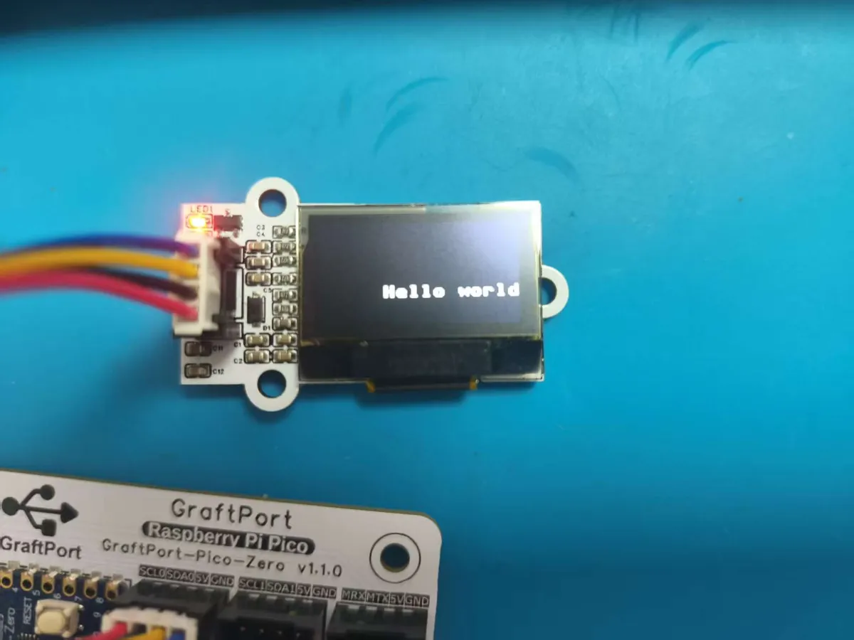 Small OLED module wired to a controller board, showing the text Hello world