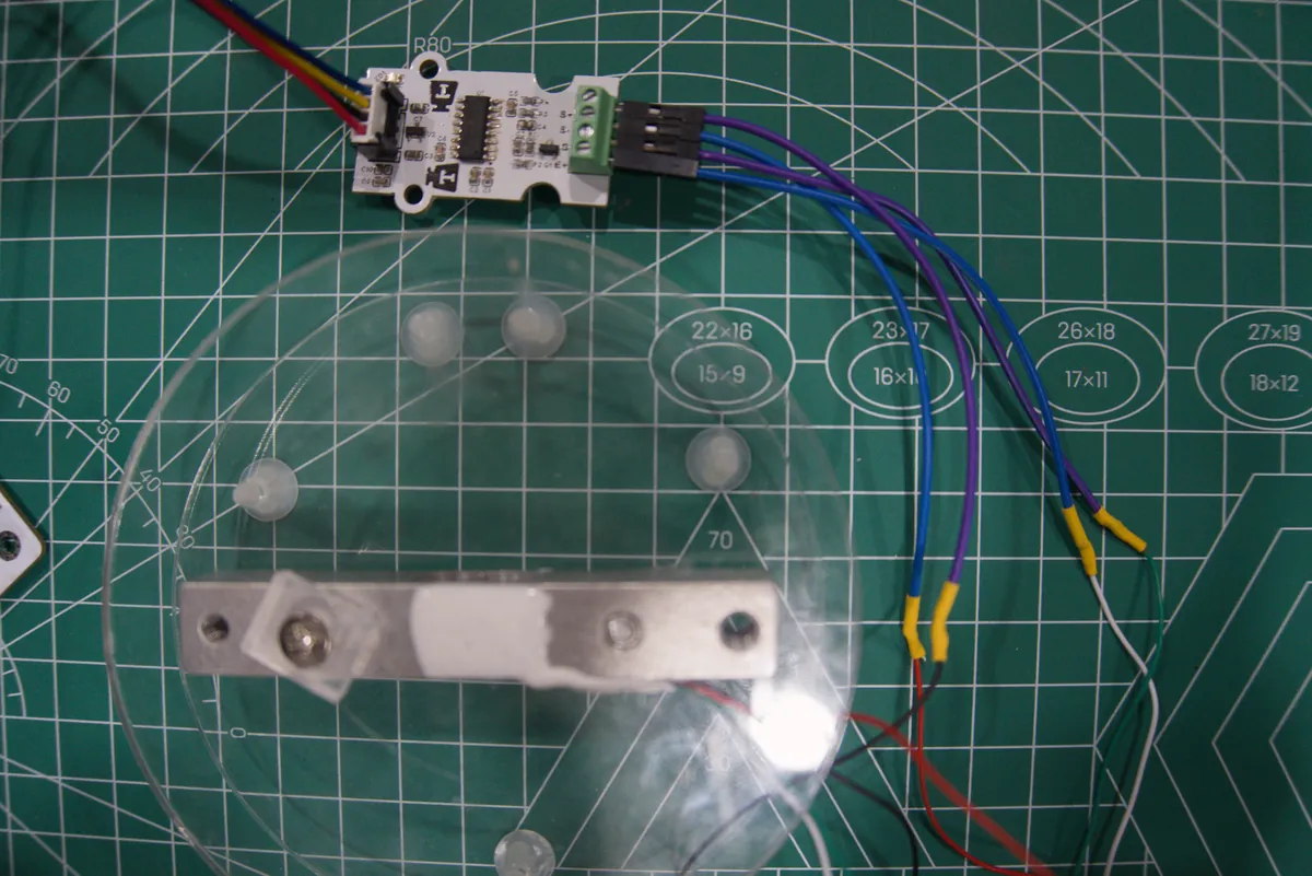 Bar load cell under a clear acrylic platform, wired through a screw terminal to an HX711 module
