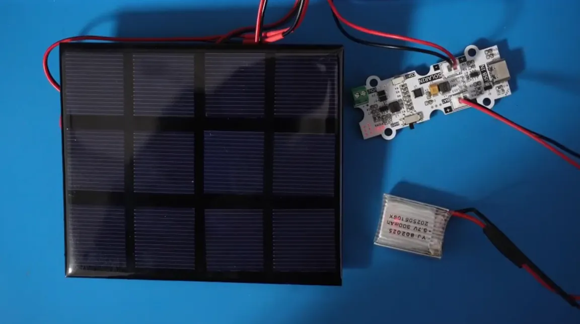 Small solar panel, SPV1050 power-management board and a small lithium-polymer cell wired together on a blue bench mat