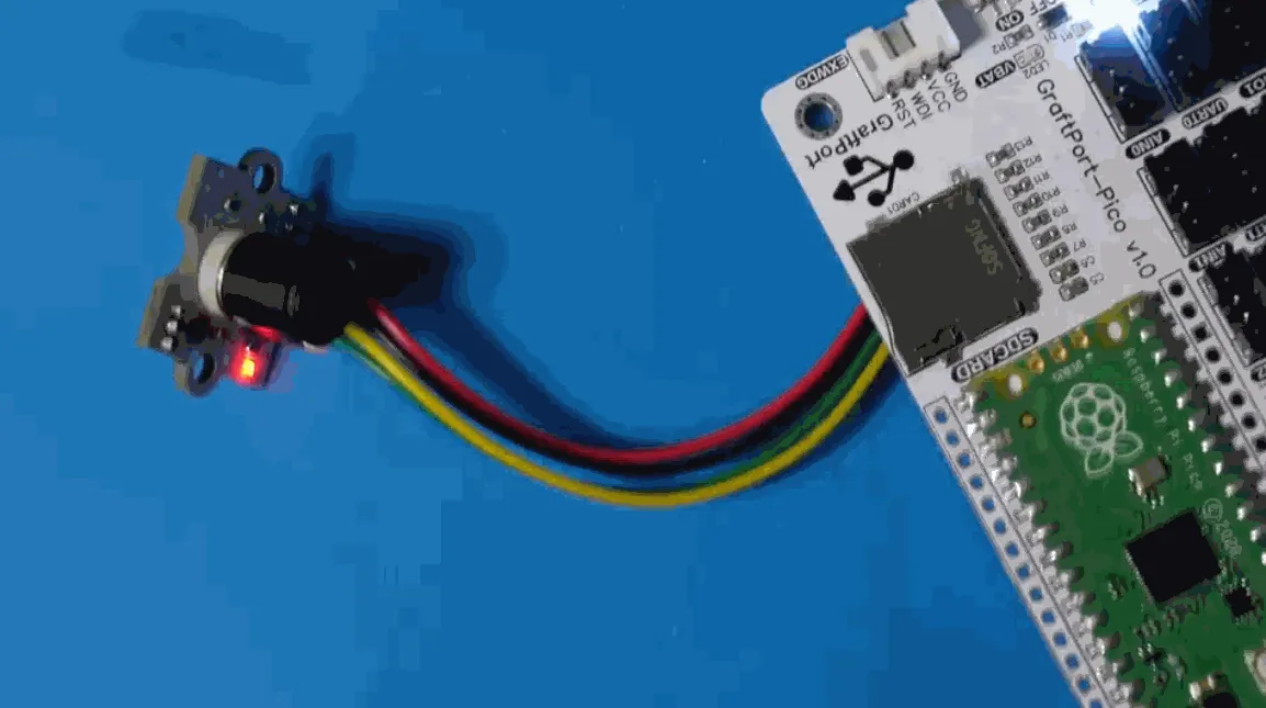 MLX90640 module on a short four-wire cable connected to a carrier board with a Raspberry Pi Pico, on a blue bench mat