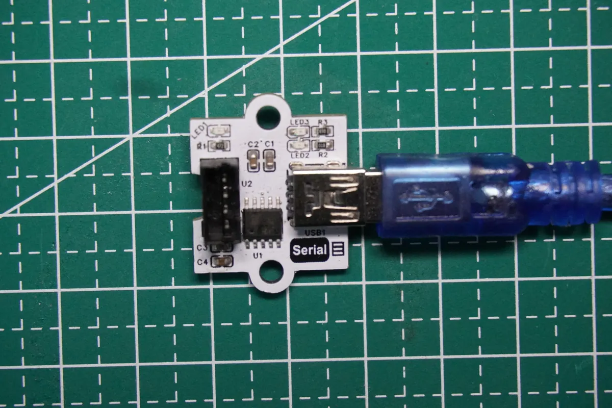 CH340K USB-to-serial module on a cutting mat with a blue Mini-USB cable plugged in